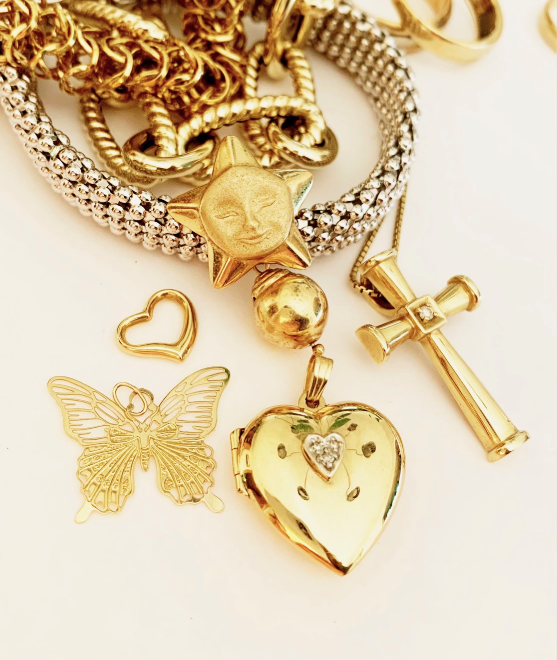 Assortment of gold jewelry including heart pendants, a star-shaped charm, and a cross with diamond, available for purchase or sale.